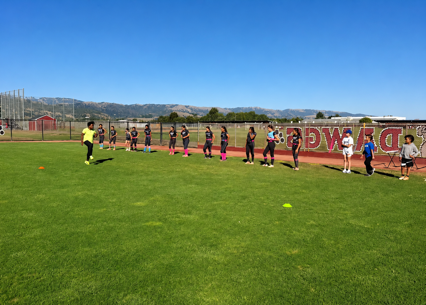 Full softball team lined up on the grass during a structured Coach Jo team training session
