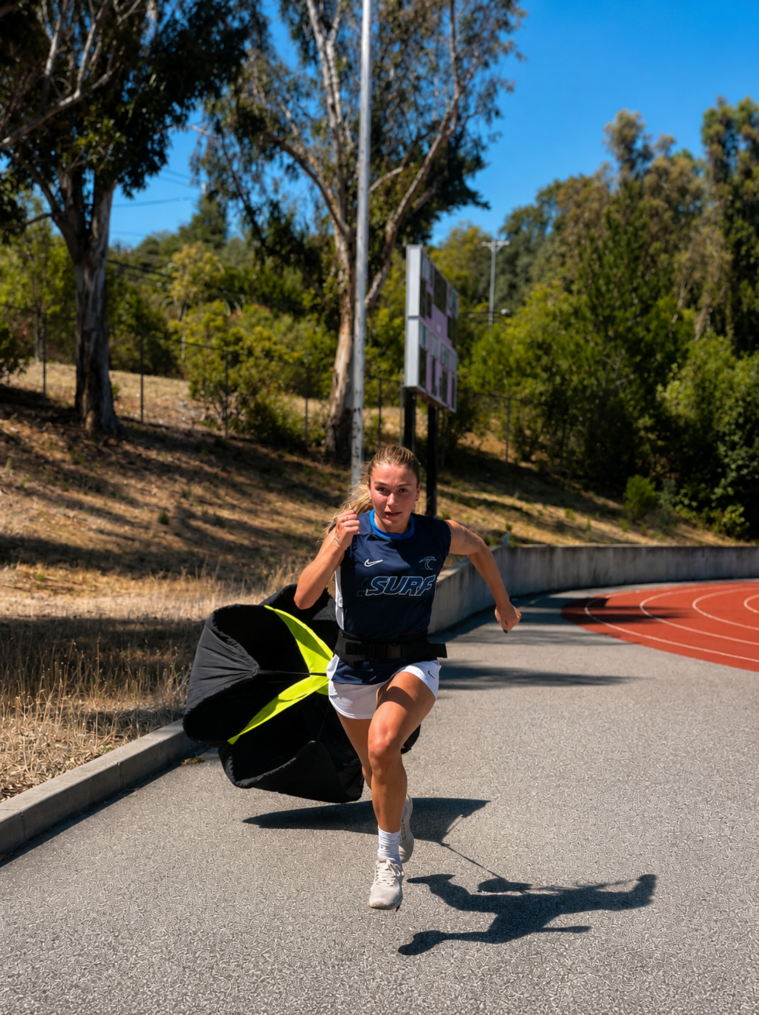 Athlete sprinting with a resistance parachute on the track for speed and power development